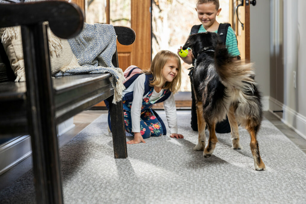 Kids plying with dog on carpet flooring | Barrett Floors